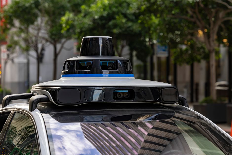 Detailed view of sensors atop an autonomous car, showcasing advanced technology in an urban setting.